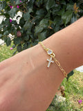 Pulsera cruz pedrería. Laminado en oro 14k.