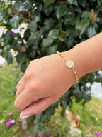 Pulsera cruz pedrería. Laminado en oro 14k.