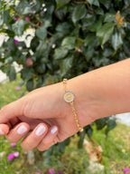 Pulsera cruz pedrería. Laminado en oro 14k.