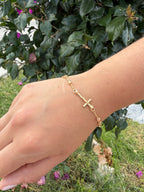 Pulsera cruz pedrería. Laminado en oro 14k.