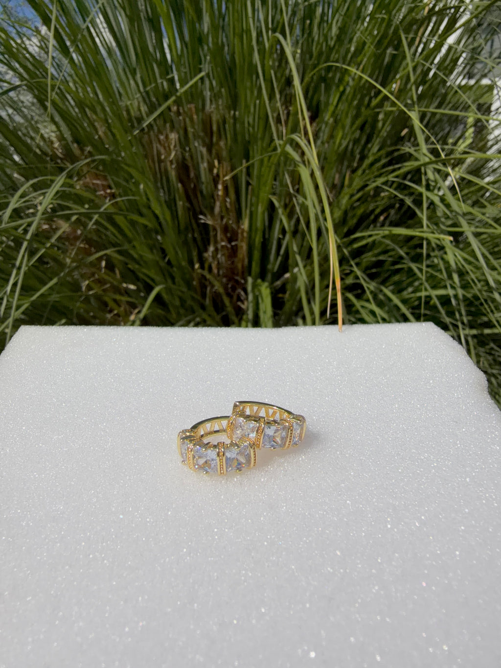 Arete huggie con pedrería. Laminado en oro 14k.